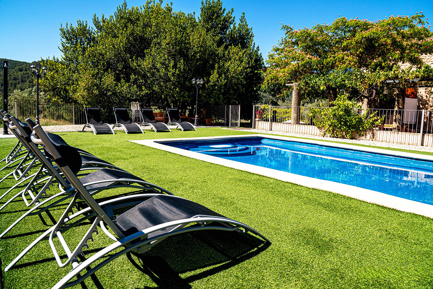 Piscina exterior con tumbonas y césped de l'Alqueria del Pilar